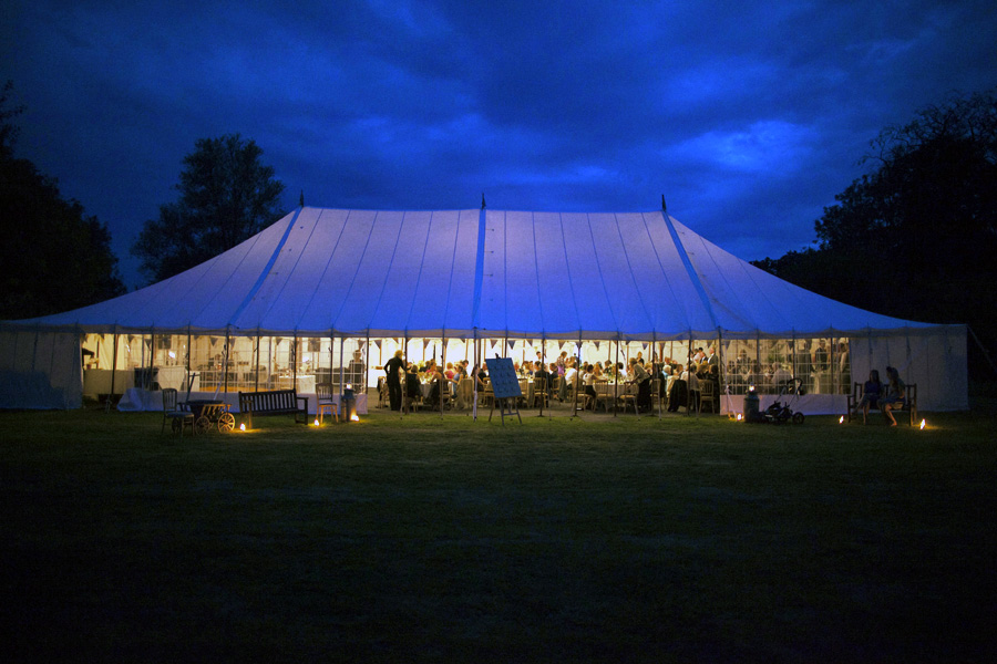 Glowing canvas marquee at dusk during a wedding