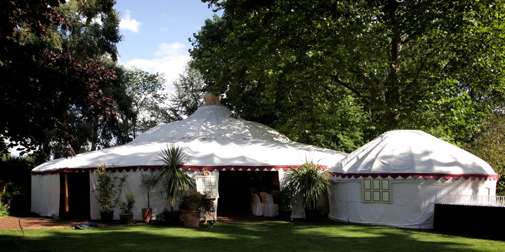 Round yurt-style pavilions with domed roofs in a garden